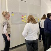 Verschillende mensen met elkaar in gesprek bij een bord met post-its